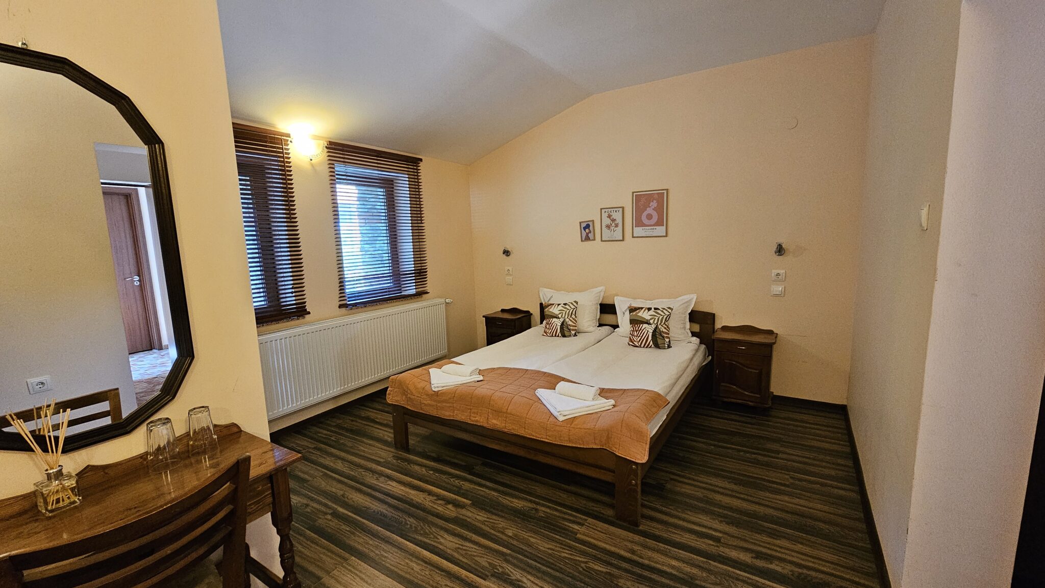 Double bed with an orange throw, table and chairs by the window
