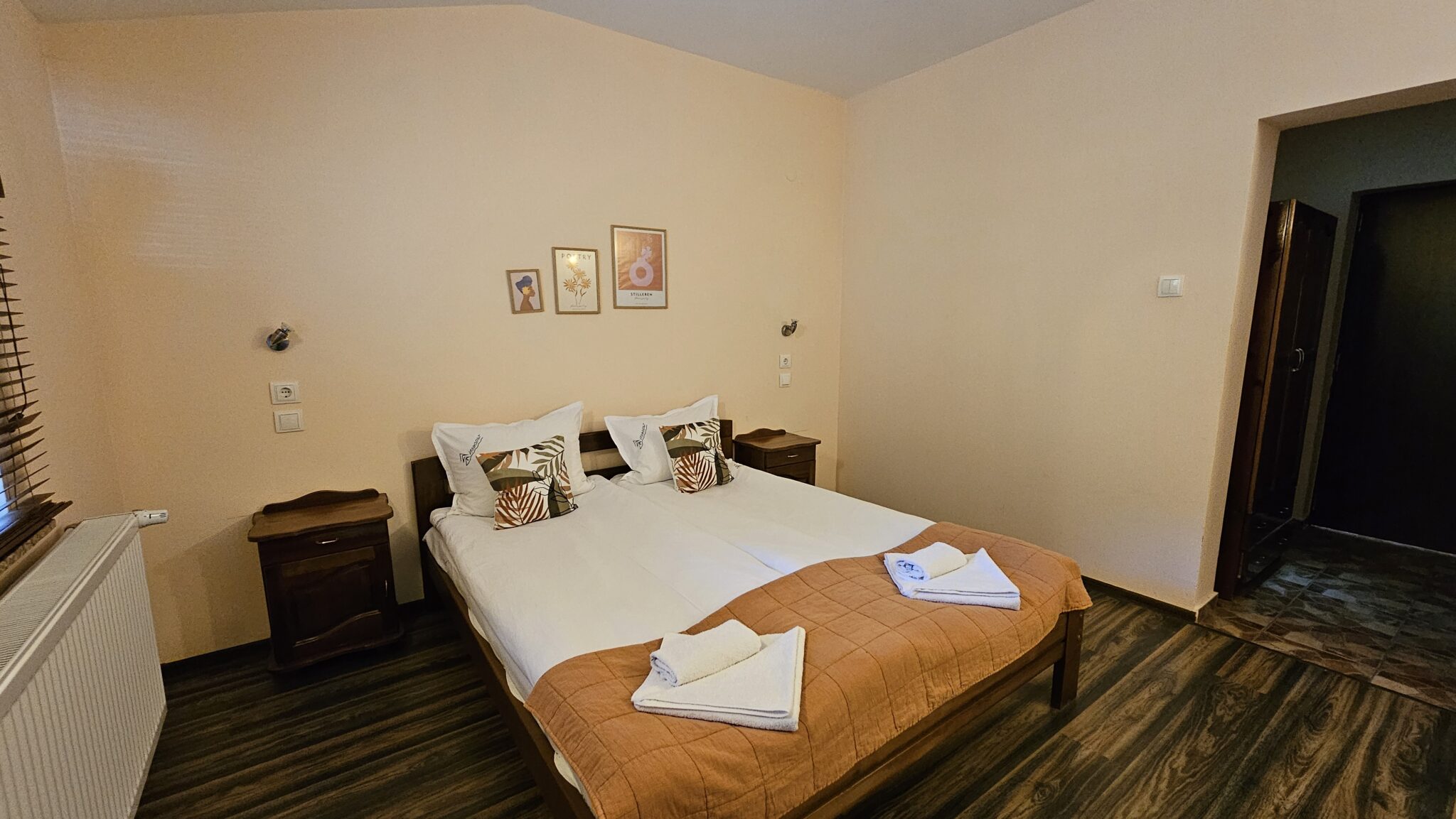 The double bed with an orange throw and pictures above it