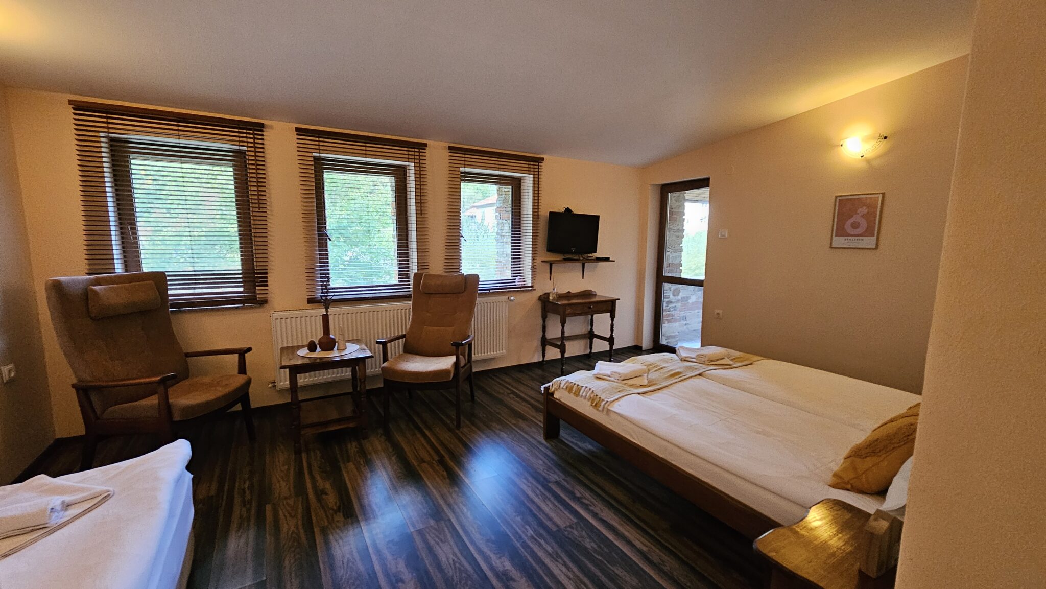 Double bed, two armchairs with a small table, and a television