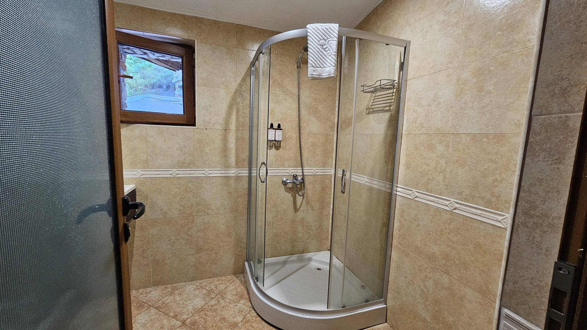 The bathroom: corner shower cabin and a small window