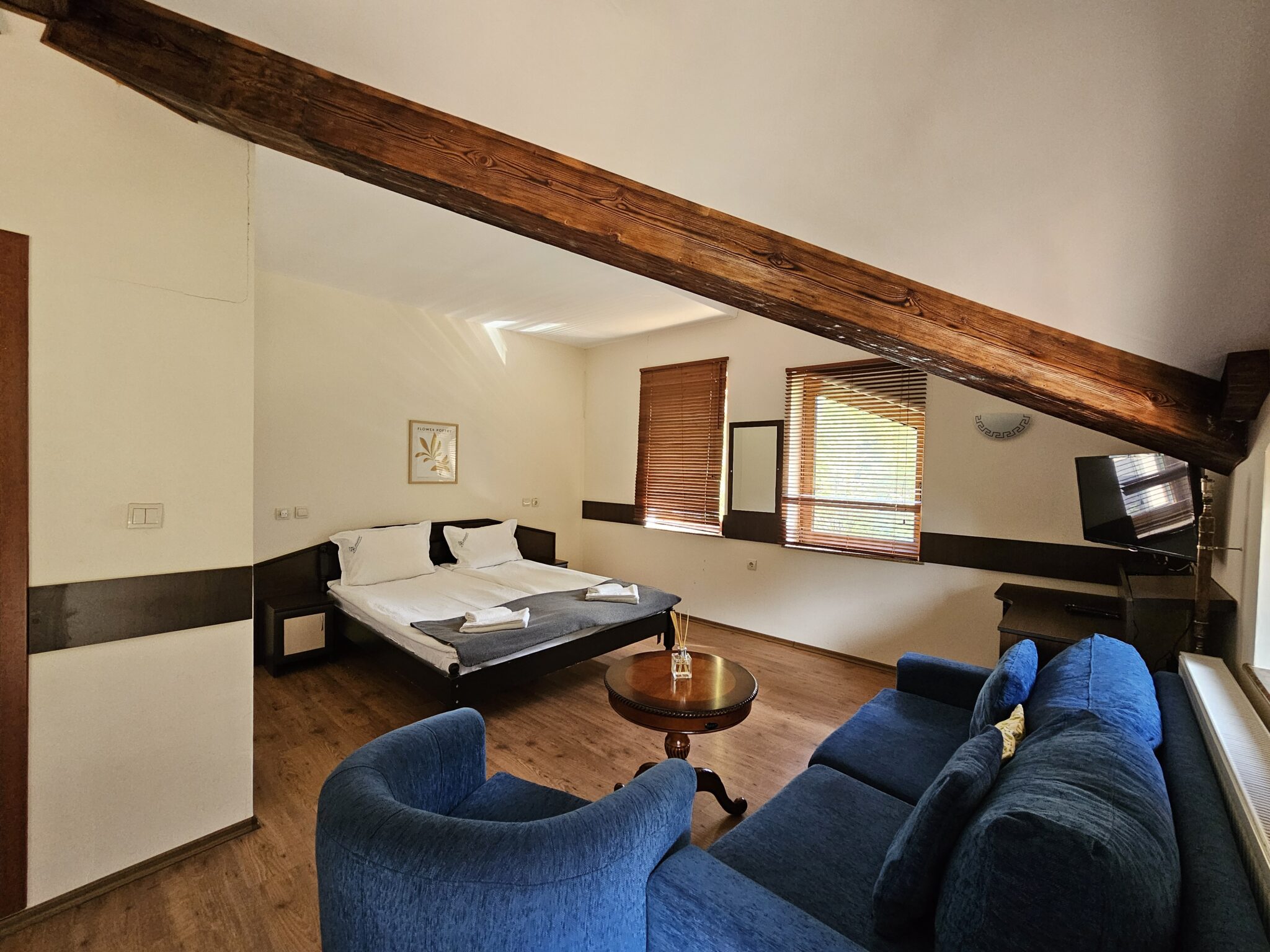 Attic room with an exposed beam, a blue sofa and armchair