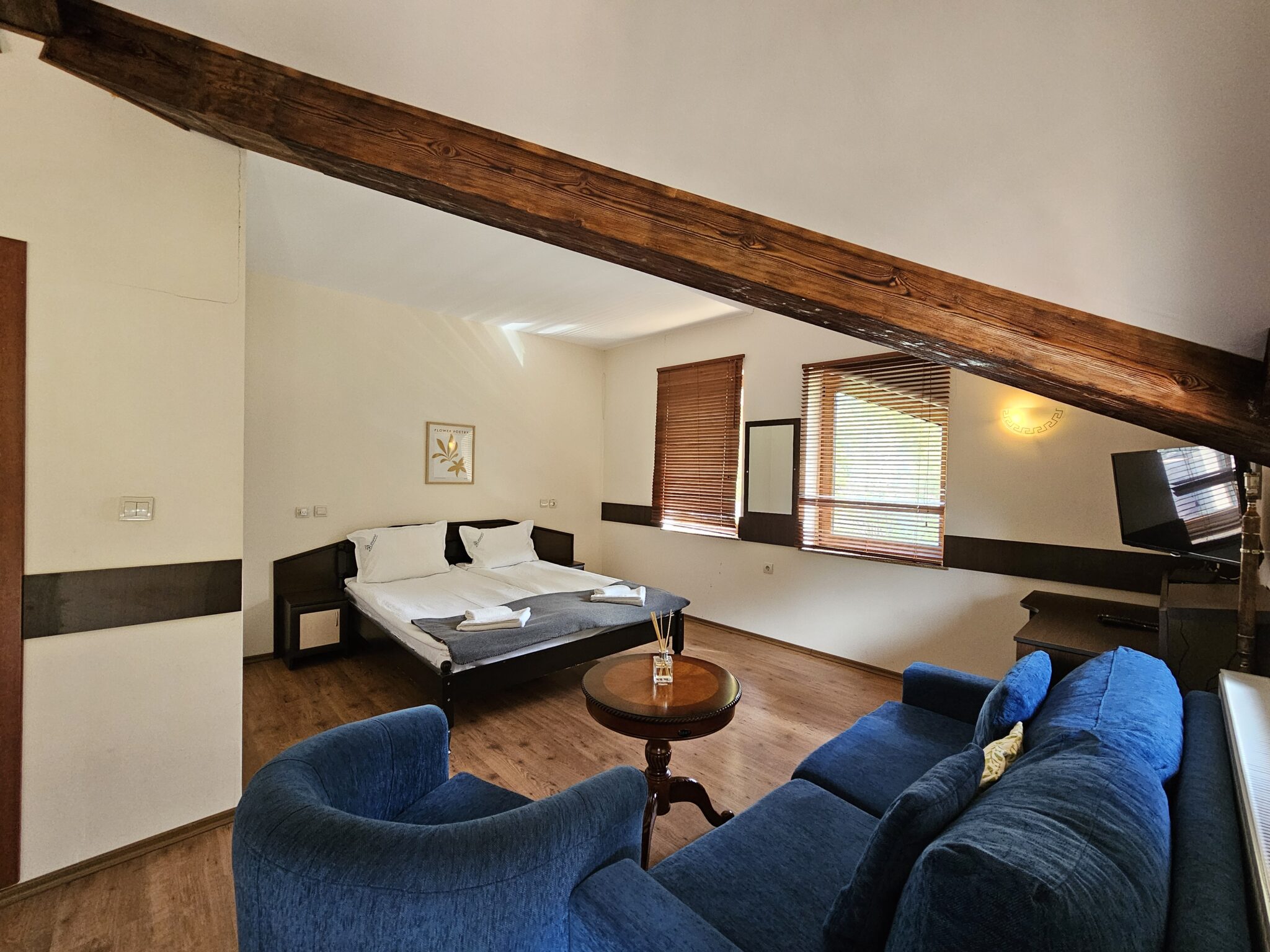 The blue sofa with a small table, the bed behind under the beam