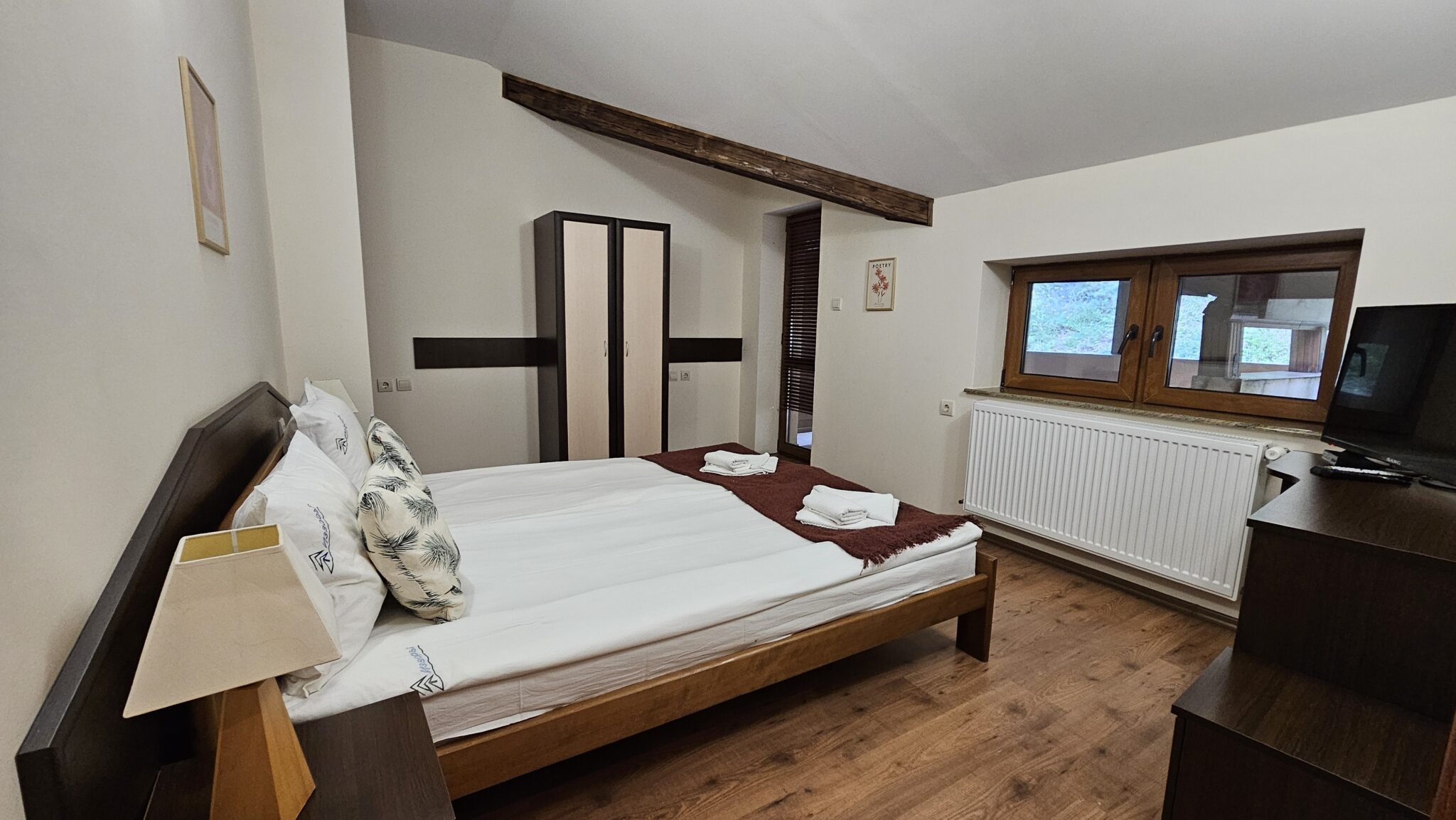 Double bed with white linen, a wardrobe and a window
