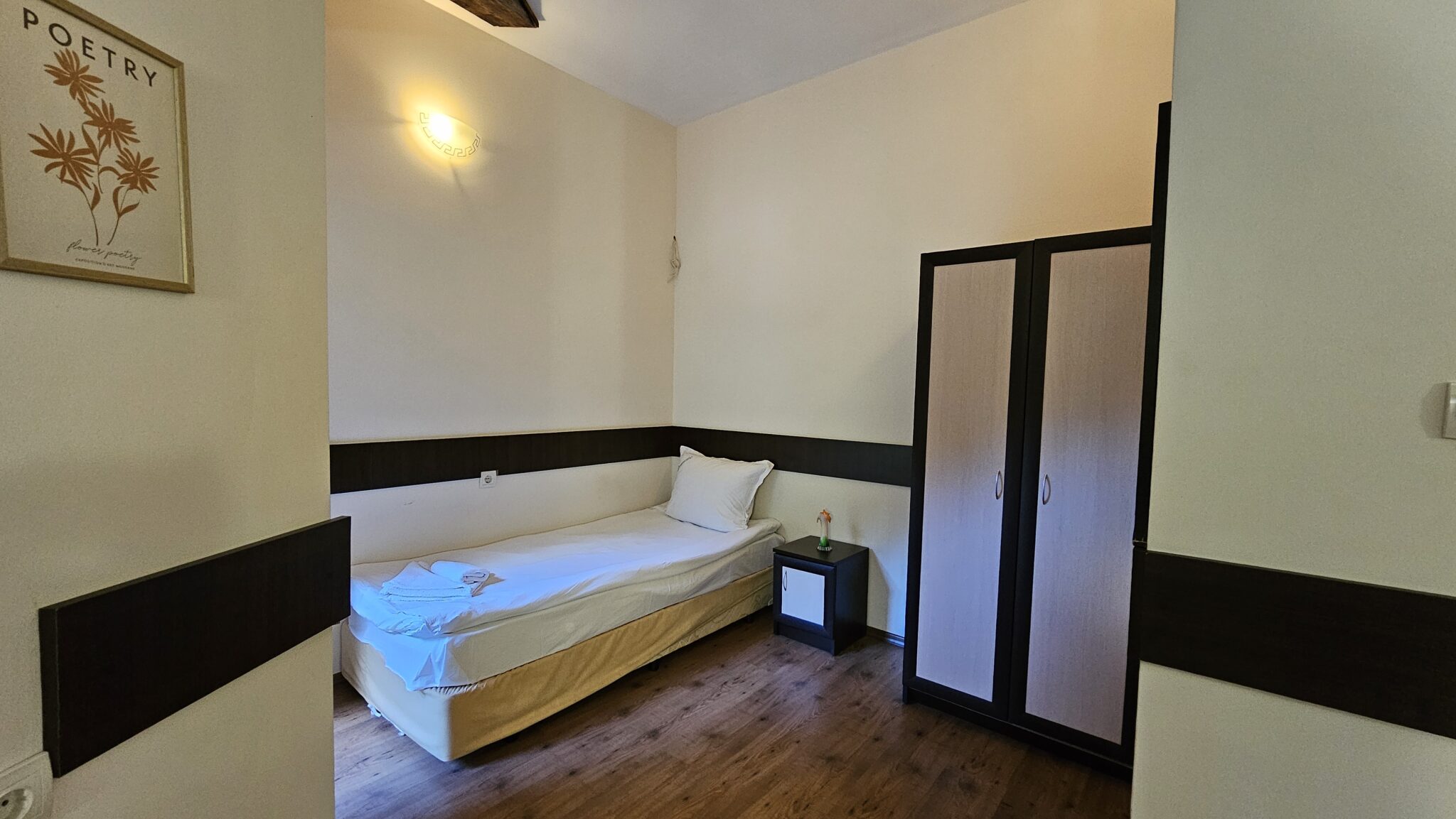 One of the single beds with the wardrobe beside it
