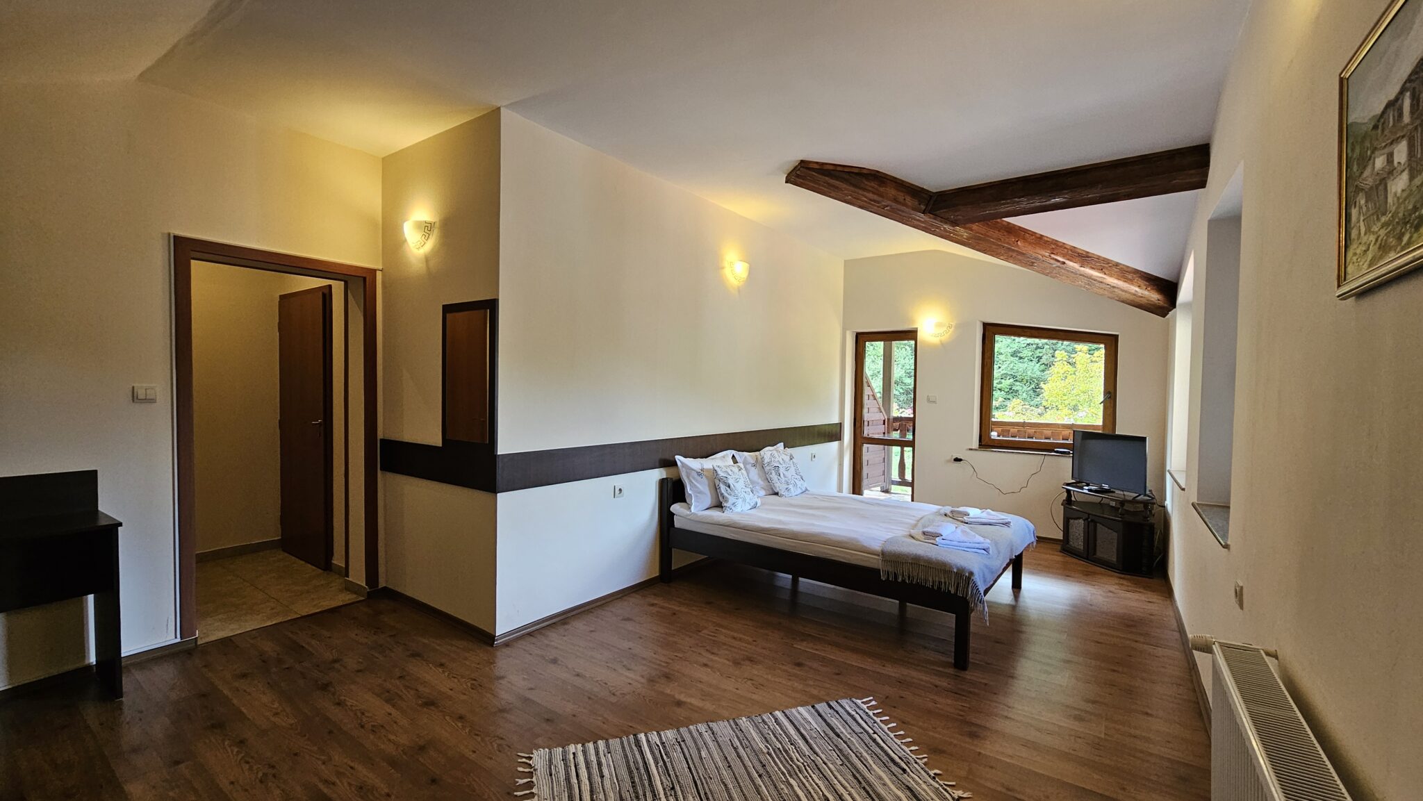 The room from the doorway — bed, television and balcony door