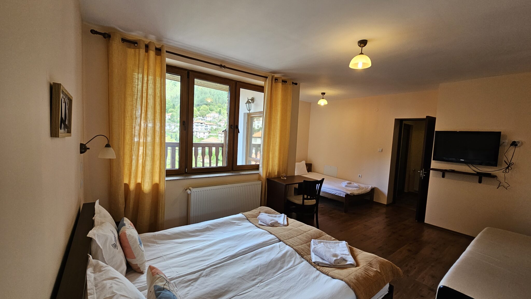 The window with yellow curtains, the second bed behind